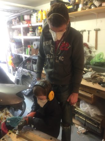 Thomas sanding the hatch trim down with the Fein multitool sporting his PPE 1